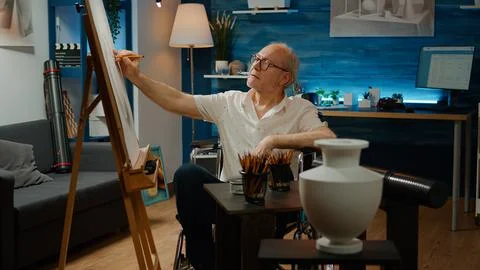 Old man with physical disability using artistic tools to draw vase Stockfoto's