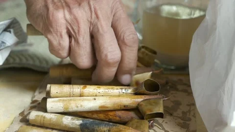 Old man picking up a canting or pen to draw batik motif Stock Footage 259463772