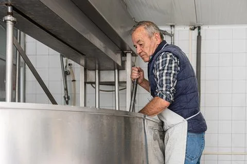Old man picking up the last bits of curd in the metal container Stock Photos