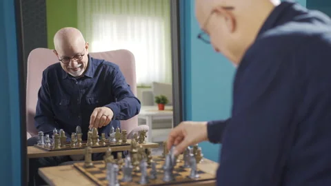 The old man is playing chess alone in front of the mirror. Stock Footage 232232237