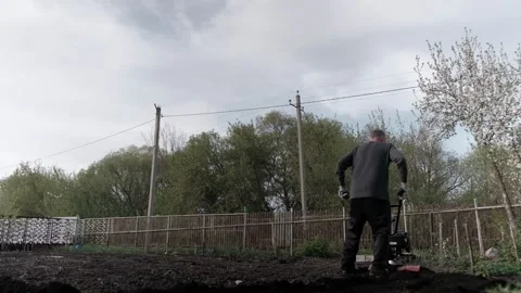 Old man plowman plows the earth with a big effort motoblock. Very hard work. 4k 動画素材 130517662