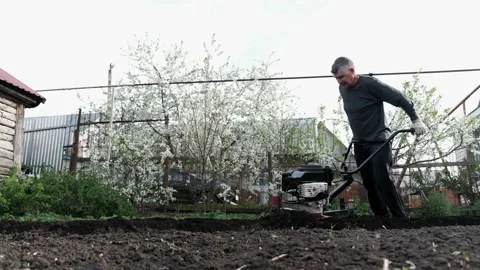 Old man plowman plows the earth with a big effort motoblock. Very hard work. 4k Stock Footage 130518014