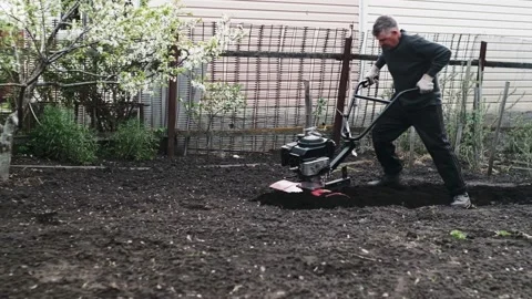 Old man plowman plows the earth with a big effort motoblock. Very hard work. 4k Video stock 130518498