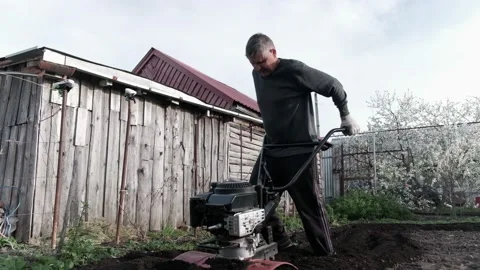 Old man plowman plows the earth with a big effort motoblock. Very hard work. Vídeos de archivo 130518973