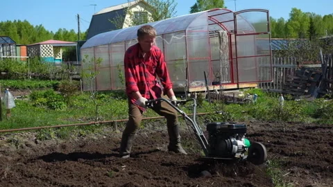 Old man plows the ground with a motor cultivator. Stock Footage 133221215