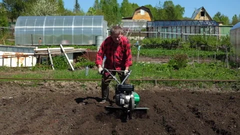 Old man plows the ground with a motor cultivator. Stock Footage 133221222