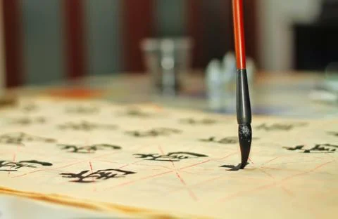 An old man is practicing callingraphy using a brush pen in his leisure time Stock Photos