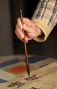 An old man practising callingraphy using a brush pen Stock Photos