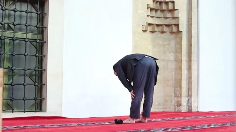 An old man praying a daily prayer on a porch of a mosque Stock Footage 147674519