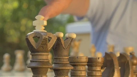 Old man prepares the chess game outside in the garden at the table and puts the Stock Footage 118701541