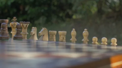 Old man prepares the chess game outside in the garden at the table and puts the Stock Footage 118714540