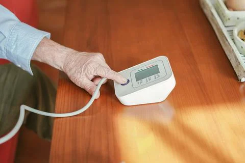 Old man presses the start button to take his blood pressure Stock Photos
