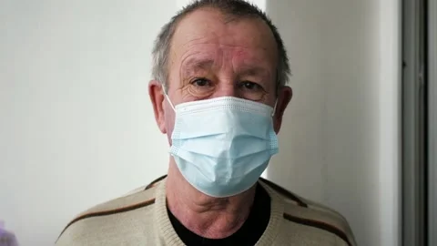Old man in a protective mask looking at the camera, portrait, self-isolation 4K Stock Footage 147067445