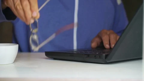 Old man puts aside glasses working on laptop close view Stock Footage 118459295