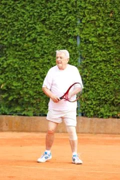 Old man with racket wait for returning ball Stock Photos
