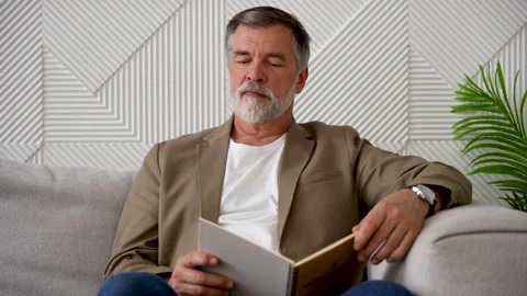 An old man reading a book in his peaceful home Video stock 278980367