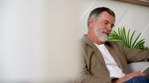 An old man reading a book in his peaceful home Video stock 278980622