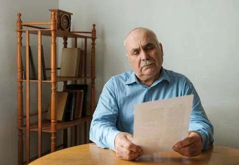 Old man reading a paper document or letter Stock Photos