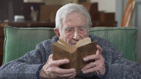  old  man reads book sitting on armchair at home Stock-Footage 74720185