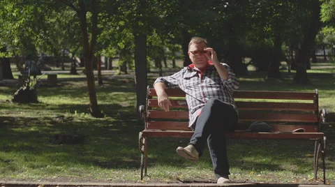 An old man reads a newspaper on a bench in the Park. Stock Footage 65905020