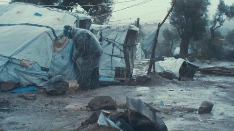 Old man refugee fixing his shelter tent in the 'Jungle' Olive Grove of Stock Footage 106458494
