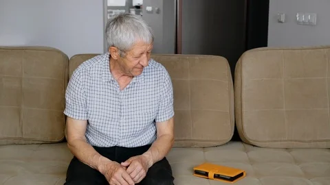 Old man retired sitting on the couch and watching photos Stockbeeldmateriaal 111527306