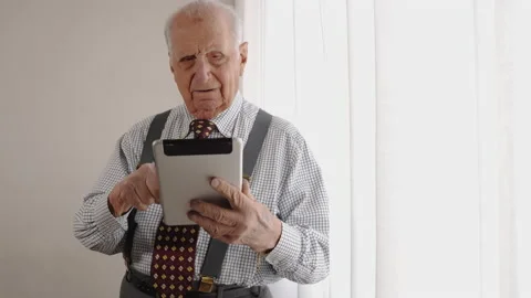 Old man in retirement using modern tablet, tapping touchscreen and scrolling Stock Footage 230034425