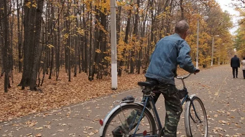 Old man rides a bicycle in autumn park at 4k 50fps Stock Footage