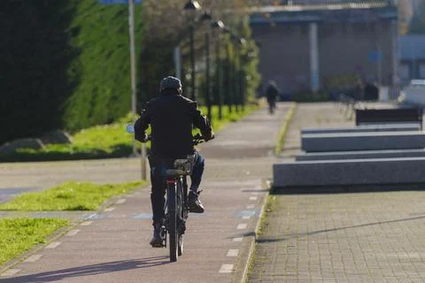 Old man is riding a bicycle down a sidewalk Stock Photos