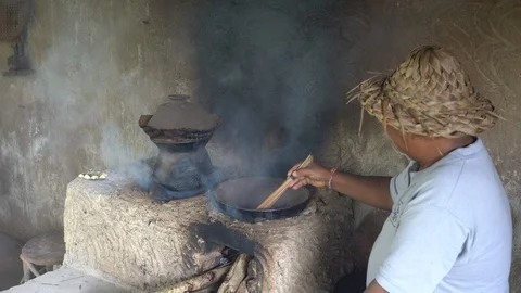 Old man roast coffee grains in pot on fire in on the kitchen, Bali, Indonesia Stock Footage 106987511