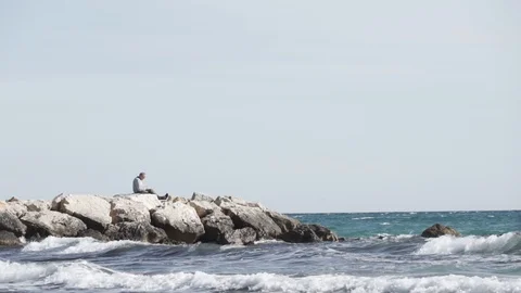 Old man on rocks in the sea Stock Footage 89692994