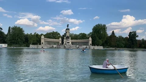 Old man is rowing a tiny boat at big pond in the Buen Retiro Park. Madrid, Spain Stock Footage 218251129