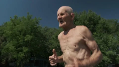 Old man runs in place against green trees at sunlight Stock Footage 201552147