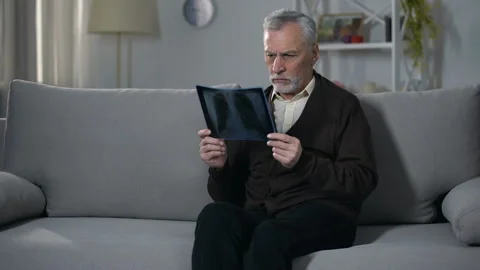 Old man sadly looking at x-ray image, difficulty coping with terminal diagnosis 動画素材 108153373