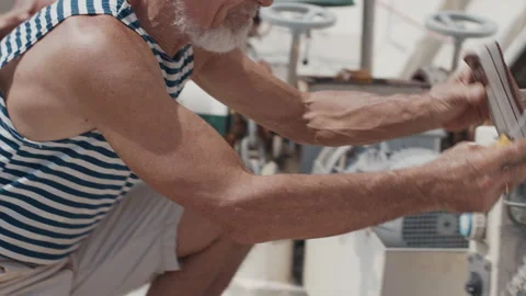 Old man sailor with white beard and ring in the ear fixes thing on the boat Stock-Footage 337992530
