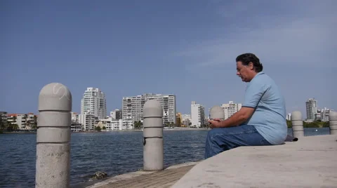 OLD MAN SENDING TEXT MESSAGE on cellphone - Condado Lagoon - Puerto Rico Stock Footage 51251442