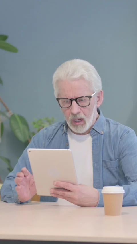 Old Man Shocked by Loss on Digital Tablet, vertical video Stock Footage 329106638