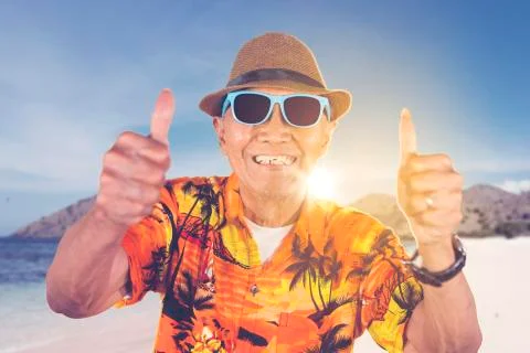 Old man show thumbs up while enjoy summer vacation Stock Photos