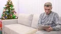 The old man sit on the sofa and talk with a tablet near christmas tree 4k or 4k+ Resolution