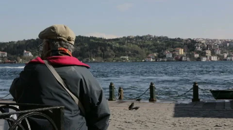 Old Man sits on a bench overlooking coast Stock Footage 46104895