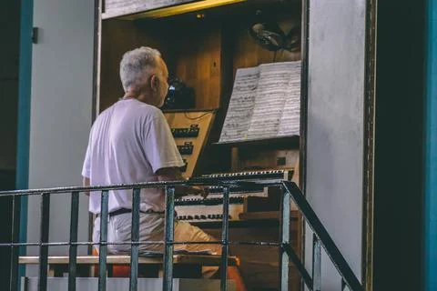 Old man sits in front of the notes and plays the organ Stock Photos