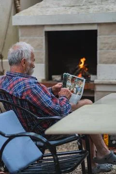 An old man sits at a table and reading newspaper. Stock Photos