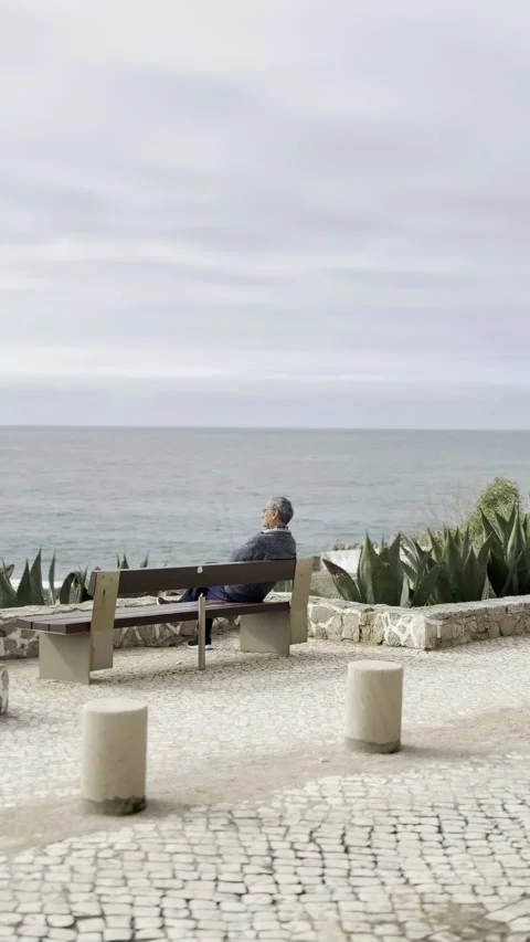 Old man sitting by the beach and pointing at something Stock Footage 304883097