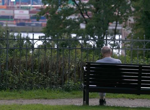 Old Man Sitting On Bench Looking Down In Park, Harbour Scenery Background Stock Photos