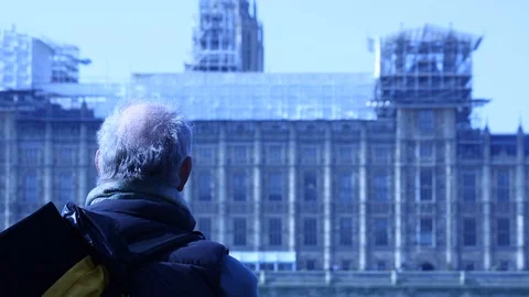 Old man sitting on bench looks out on building work Stock Footage 98723971