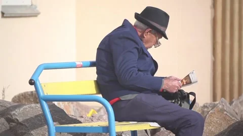 Old man sitting on a bench. reading her newspaper. pensioner Vídeos de archivo 45943524