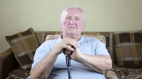 Old man sitting in a chair and holding a cane in his hands shows gesture ok Stock Footage 72992004