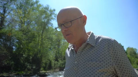 Old Man Sitting Down on Chair in River in Beautiful Nature To Eat Sandwich Stock Footage 112637826