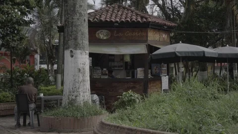 Old man sitting in-front of coffee shop in Stockbeeldmateriaal 94381841
