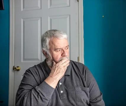 Old Man Sitting Indoors, Deep in Thought While Looking Away From the Camera Stock Photos